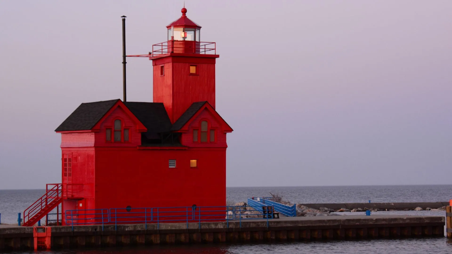 A red dutch-styled light house on a body water