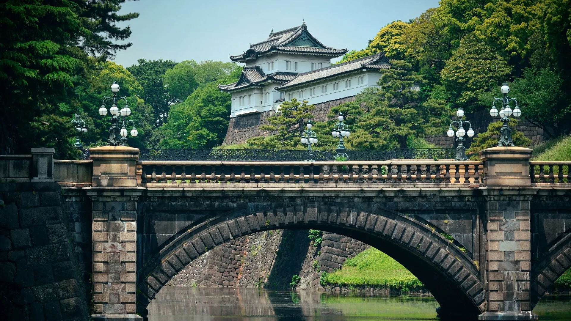 The Tokyo Imperial Castle is on a river bank over looking an old stone bridge