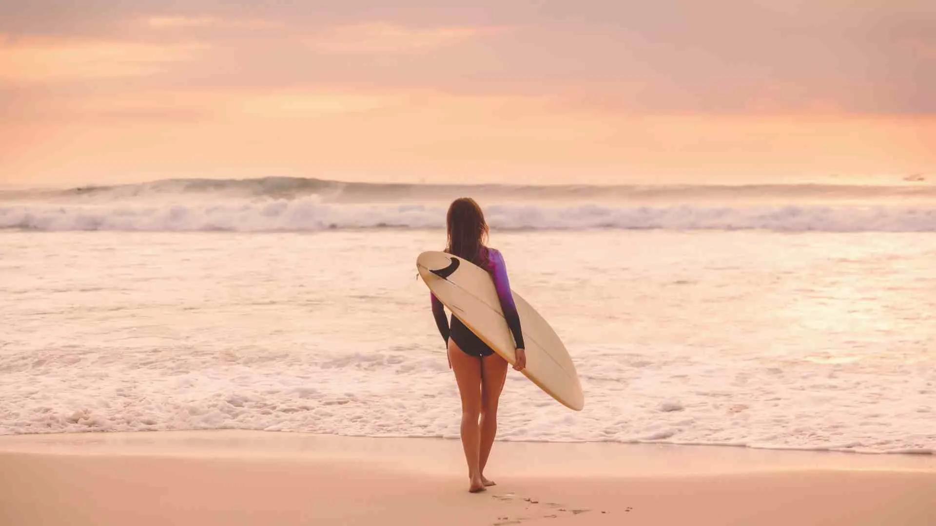 walking into the ocean with a surfboard