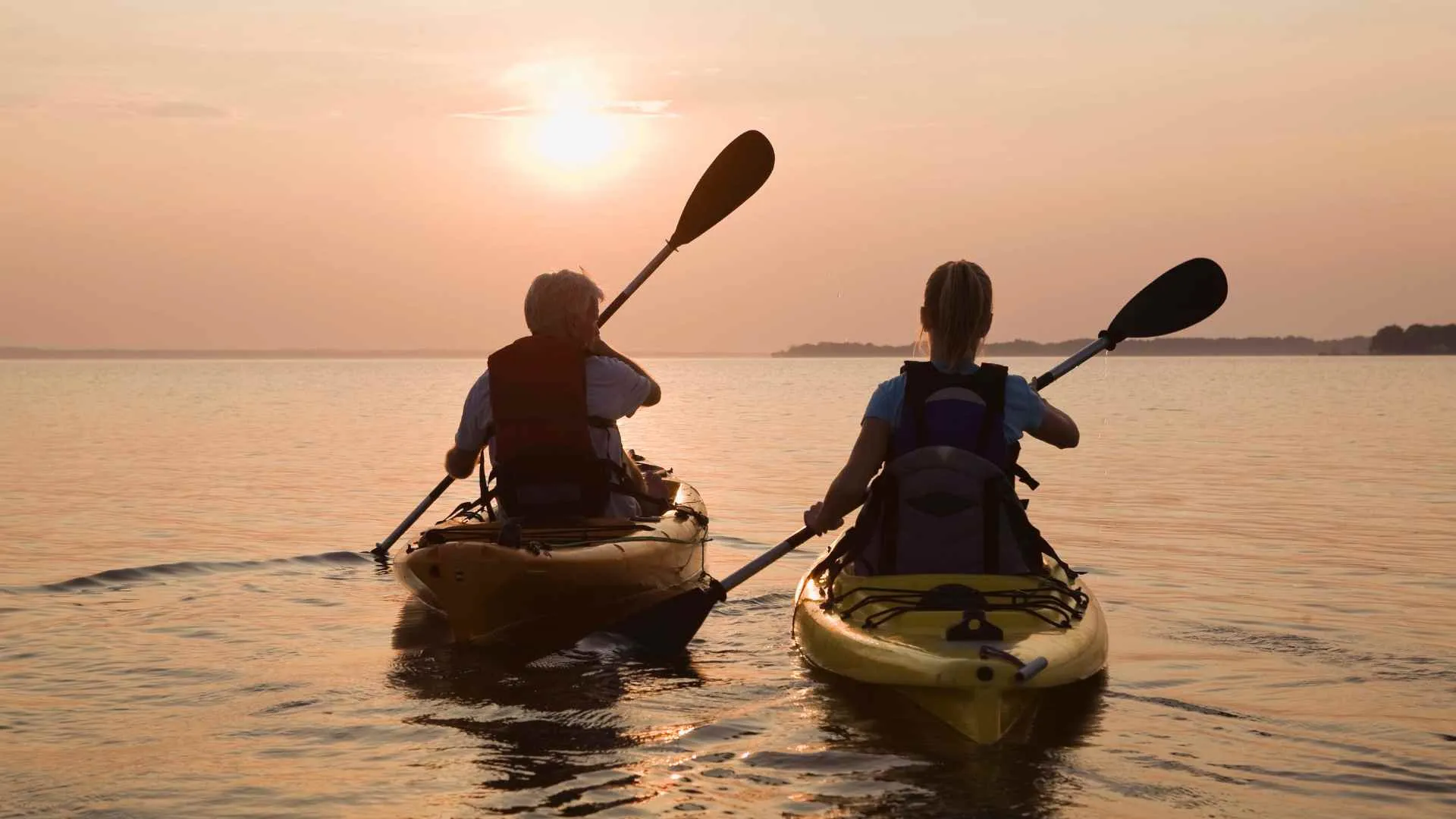 2 friends kayaking into sunset