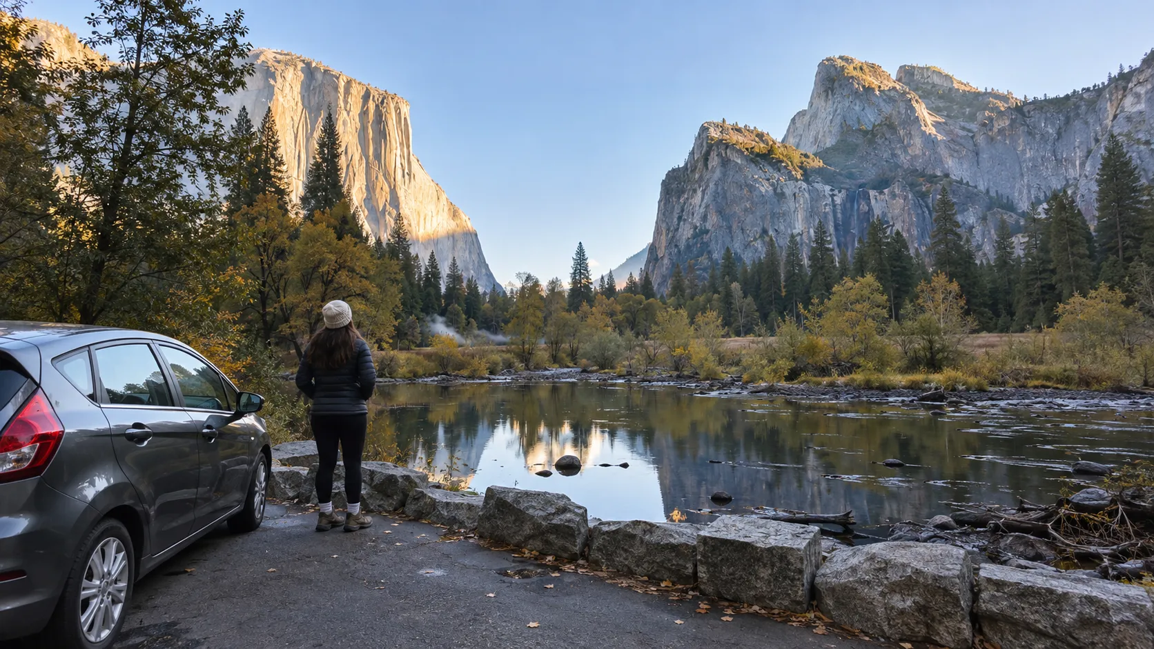 Traveler beside a parked car taking in Yosemite Valley at golden hour