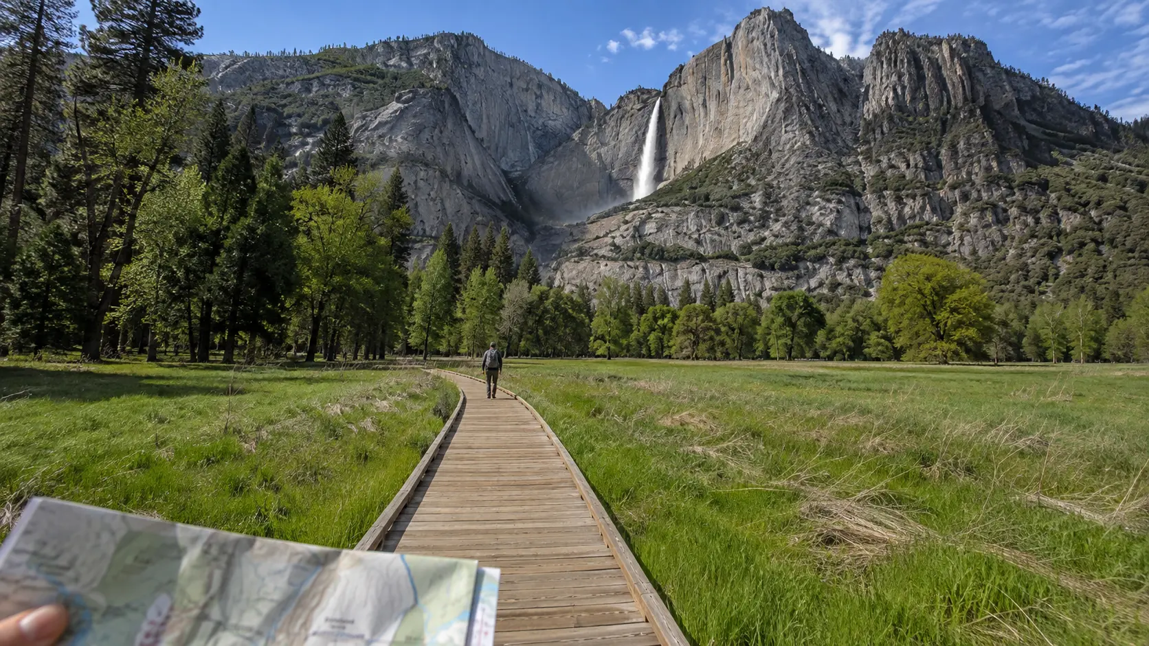 Map in hand on a Yosemite Valley boardwalk with Yosemite Falls ahead