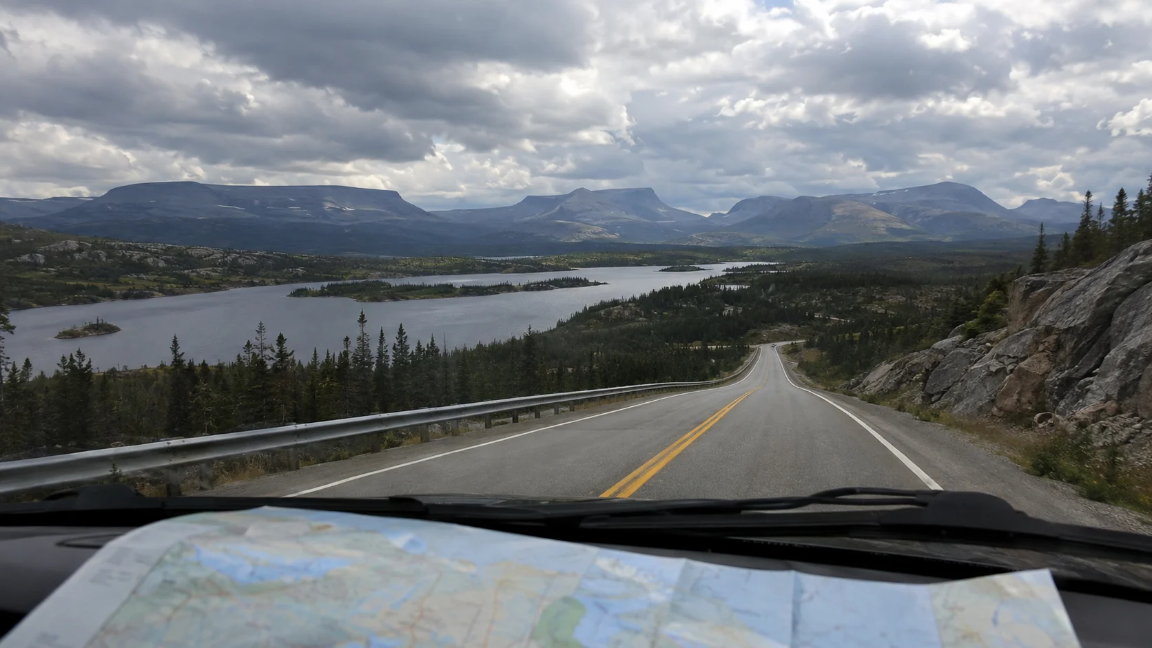 Road trip view across Newfoundland mountains and lakes from inside a car