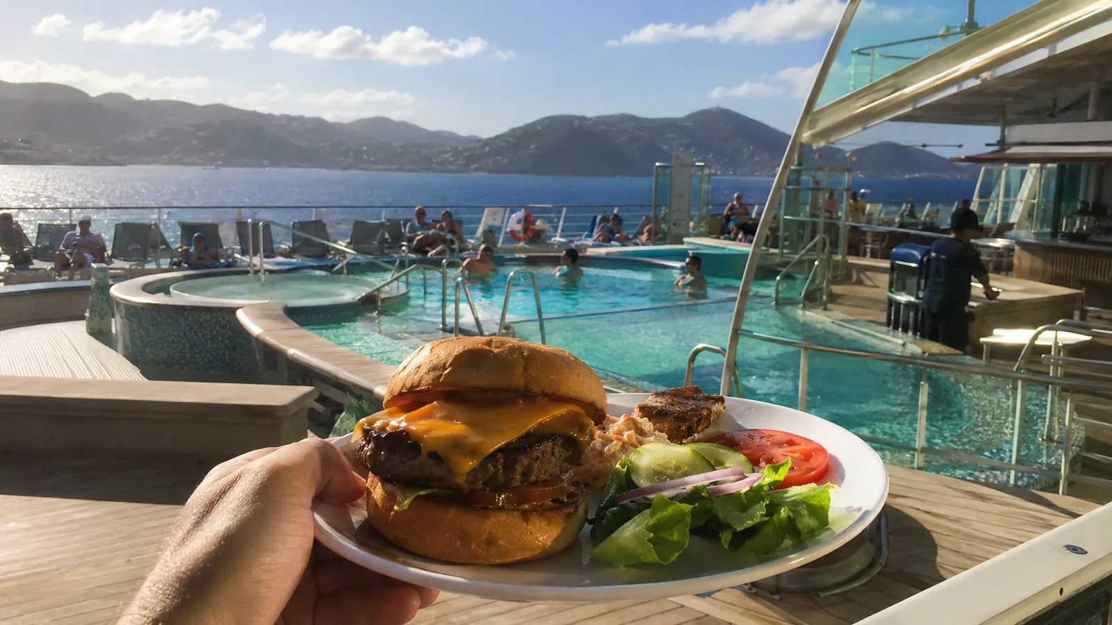 Burger and salad on a table overlooking a cruise ship pool deck