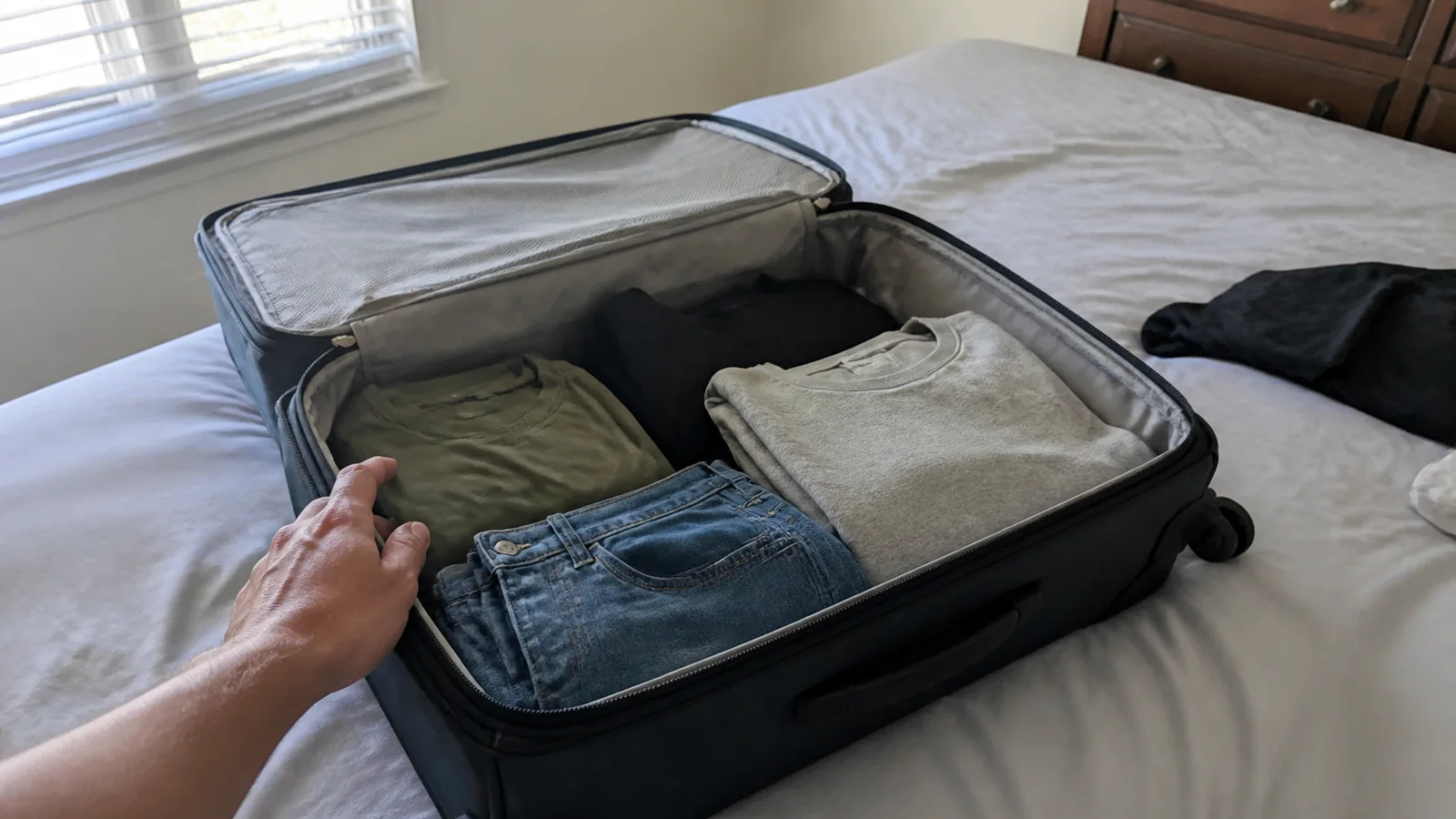 Open suitcase on a bed with neatly folded shirts and jeans.