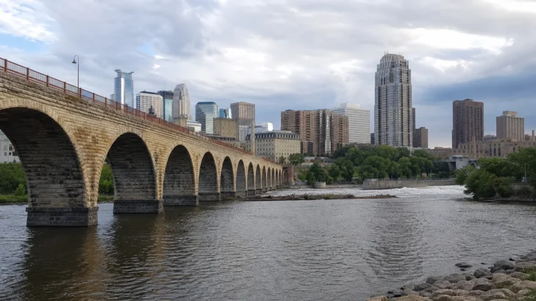 Long stone arch bridge crossing a river toward a city skyline.