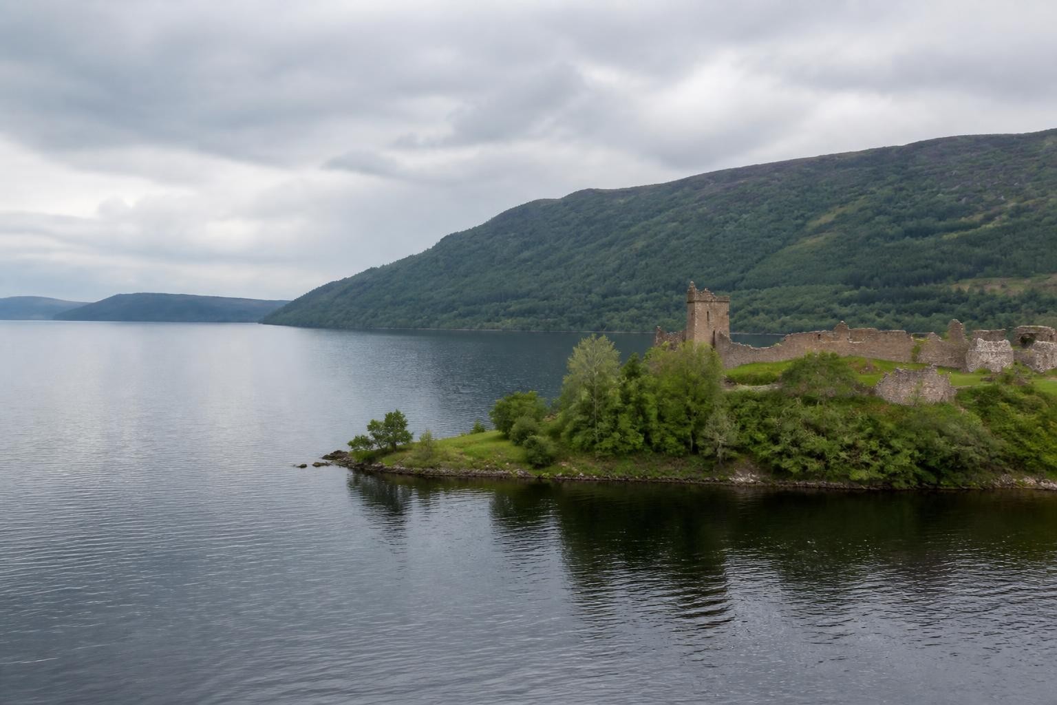 Loch Ness and Urquhart Castle beneath forested Scottish hills