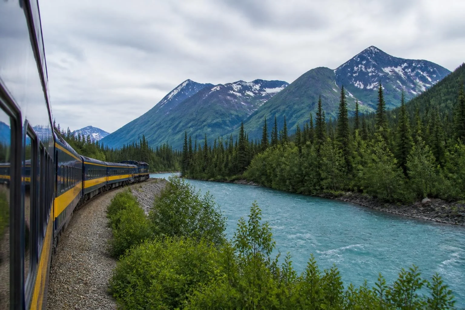 Passenger train traveling through a mountain valley in Alaska