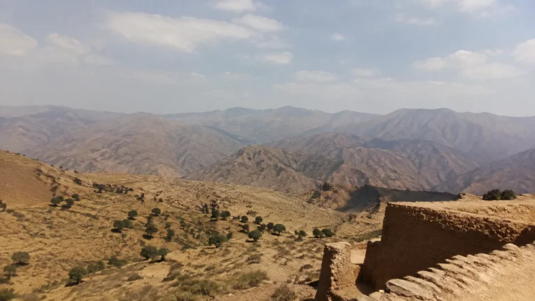 Arid mountain ridges stretch beyond an earthen wall.