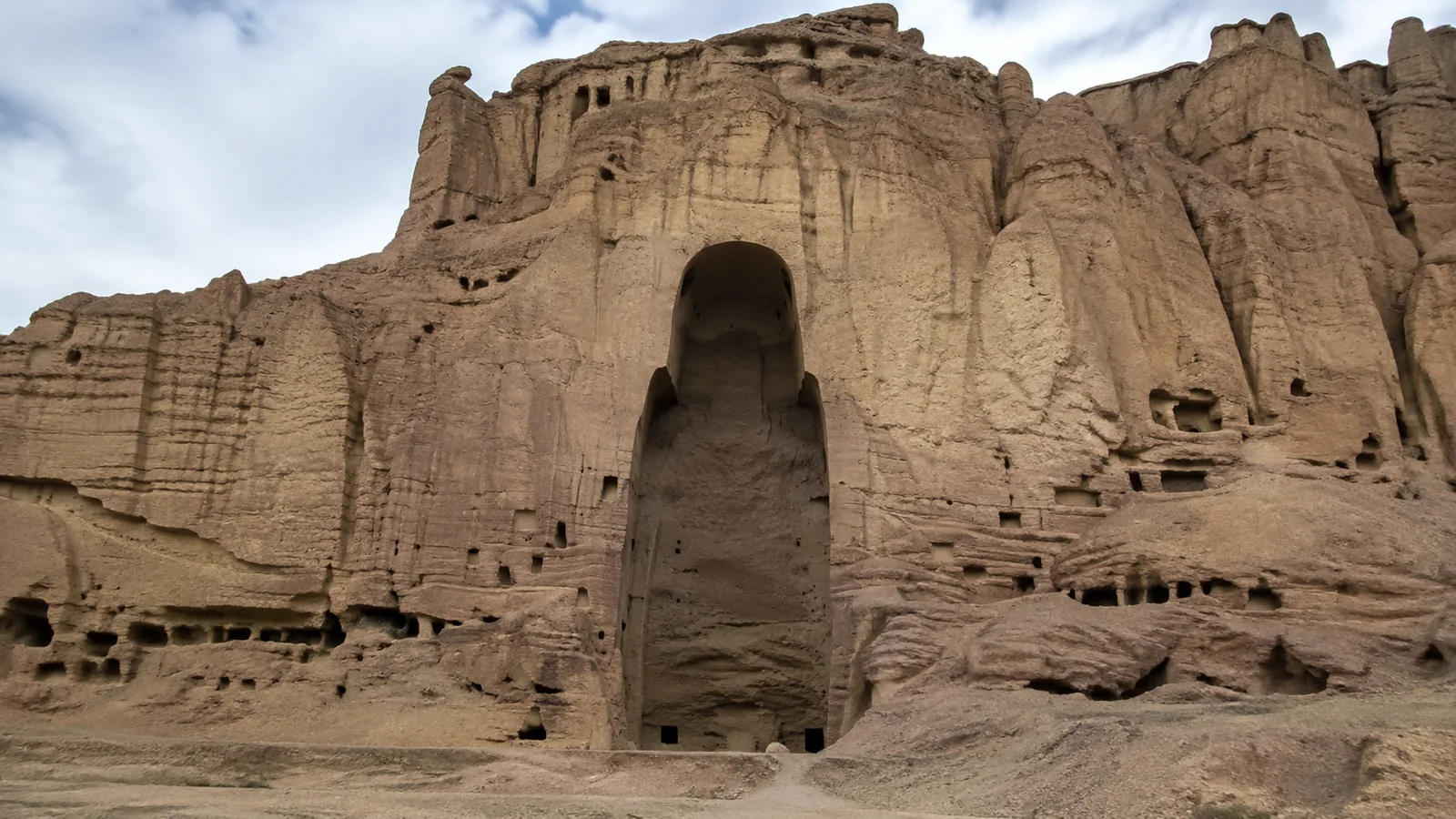 Large empty arched niche carved into a weathered cliff face.