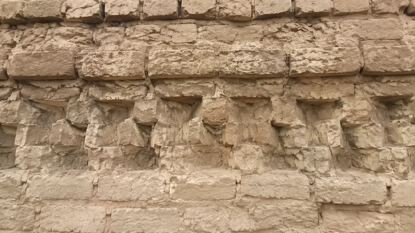 Close view of rough earthen masonry and eroded wall surfaces.