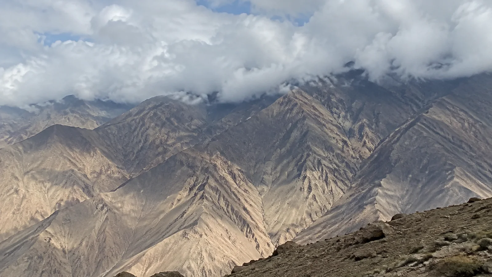 Jagged barren mountains rise beneath patches of low cloud.