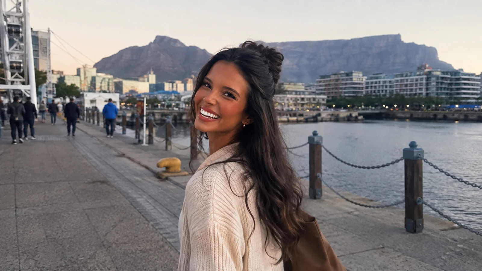 Smiling woman on a waterfront promenade with Table Mountain behind her