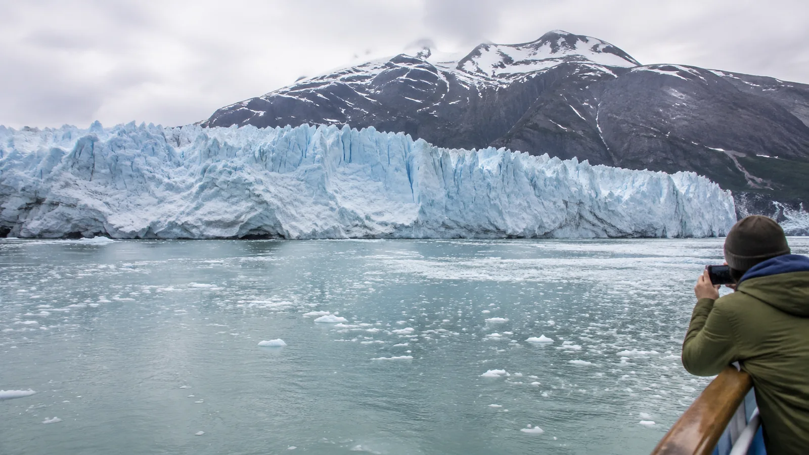 Passenger photographing a glacier across icy water