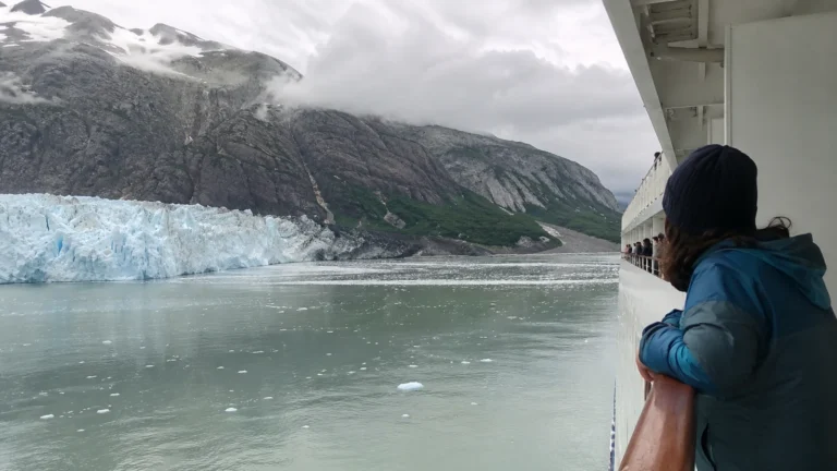 Passenger at a cruise ship railing viewing a glacier