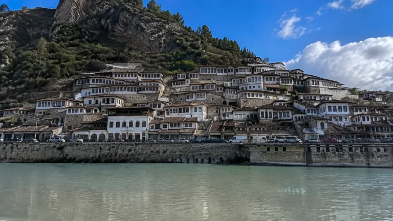 White hillside houses with dark roofs overlook a river.