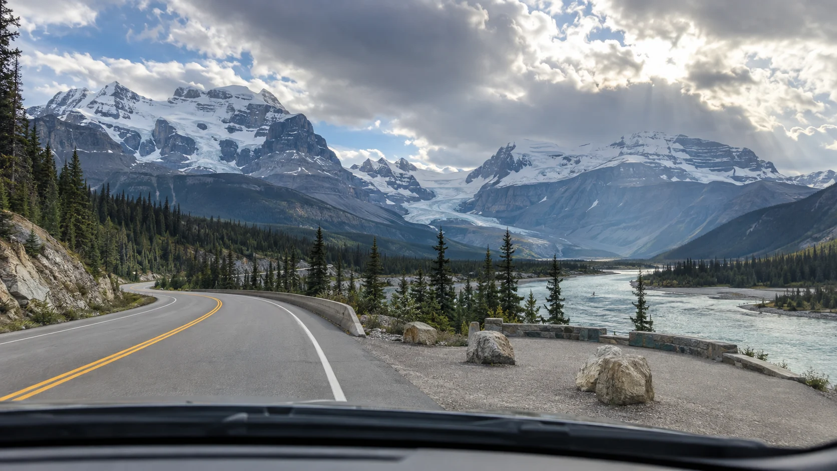 View through a windshield along the Icefields Parkway beside a glacial river and mountain icefield