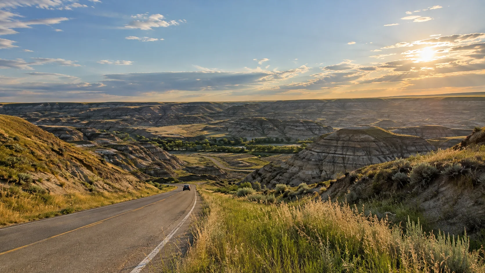 Highway descending into Alberta's layered badlands on the drive to Drumheller
