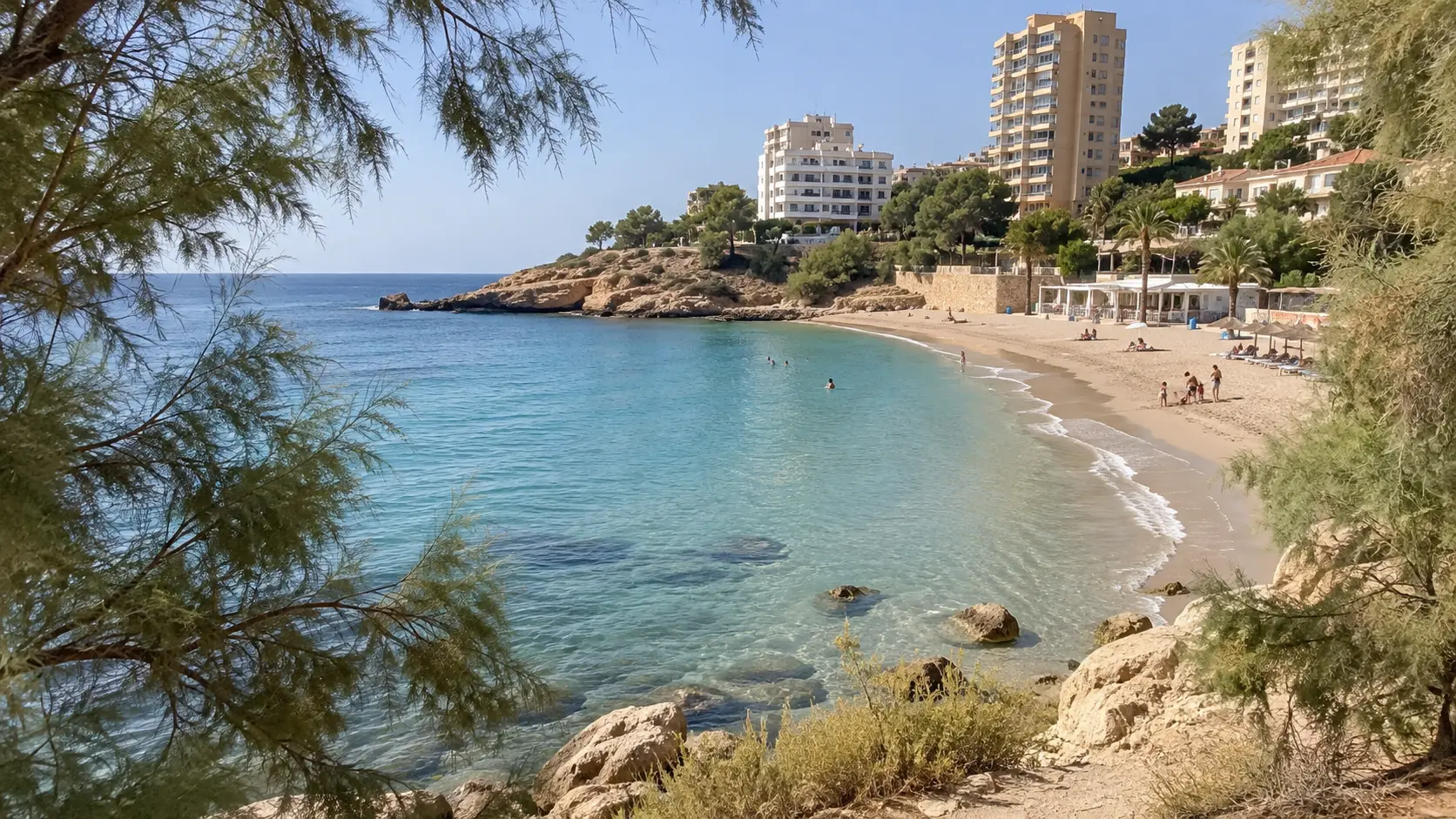 Albufereta Beach forms a compact sheltered crescent beside calm turquoise water.