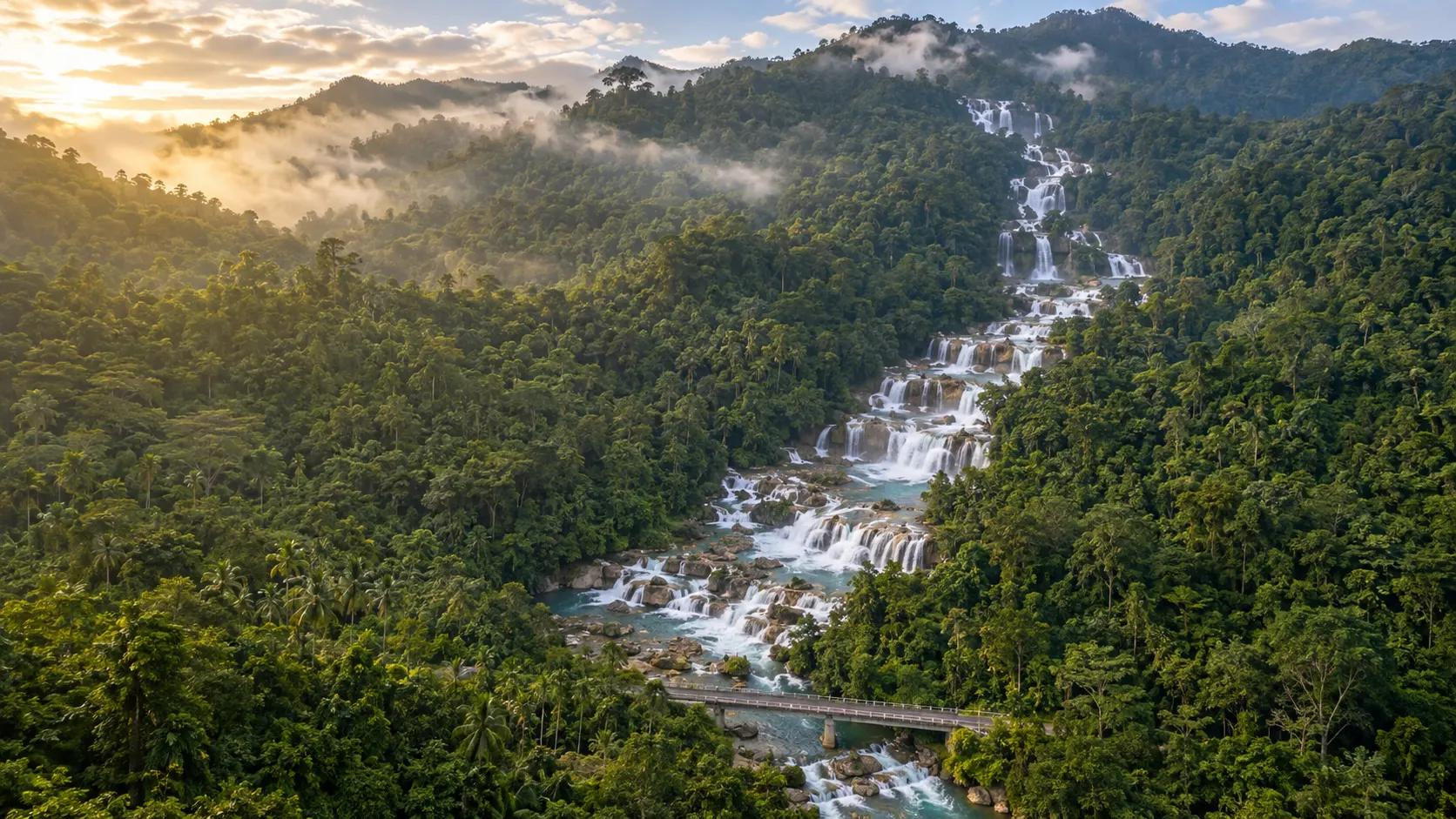 Aliwagwag Falls descending through dozens of rainforest cascades above a bridge in Davao Oriental.