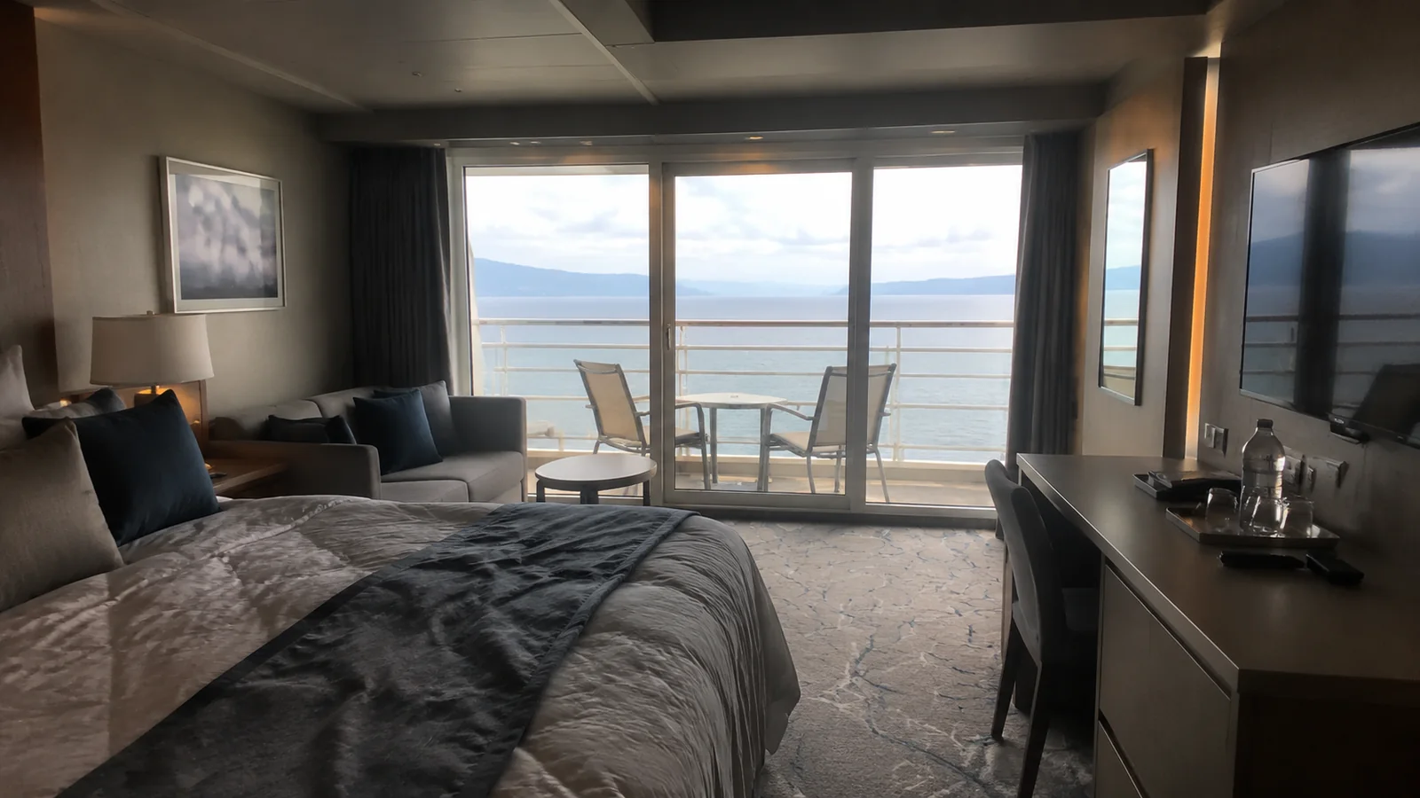 Cruise cabin with a bed and balcony overlooking the sea