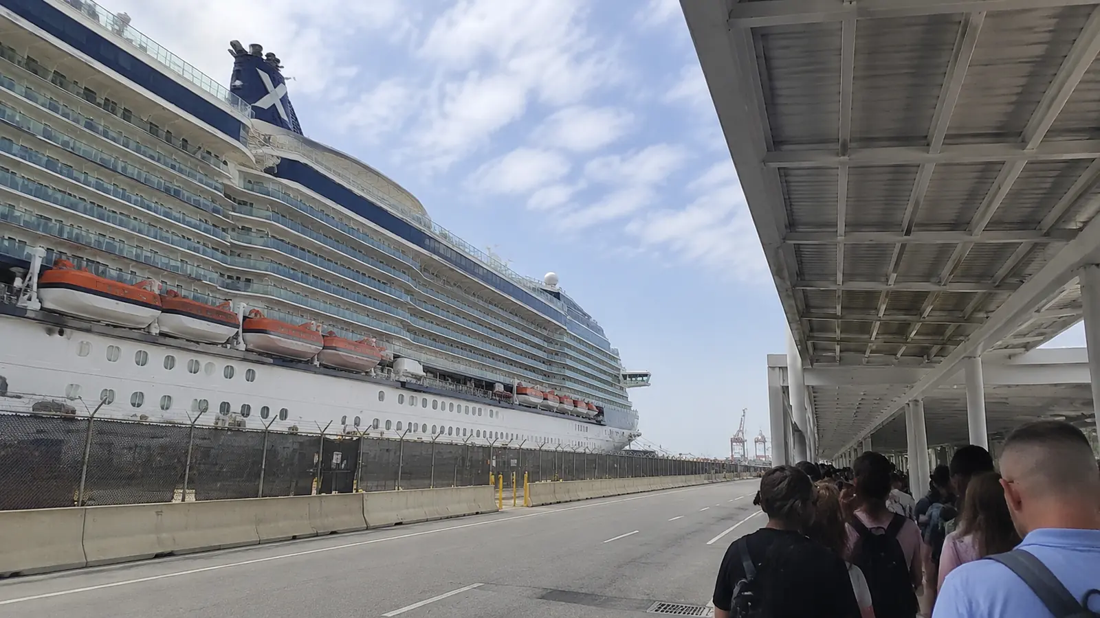 Large cruise ship docked beside a covered terminal walkway with passengers