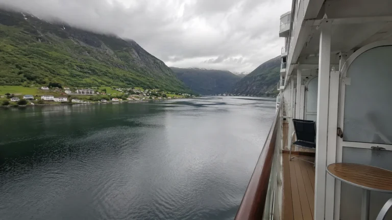 Cruise ship sailing through a narrow green fjord