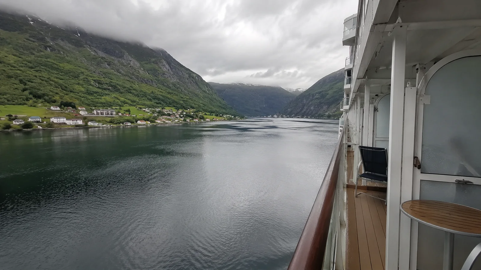 Cruise ship sailing through a narrow green fjord
