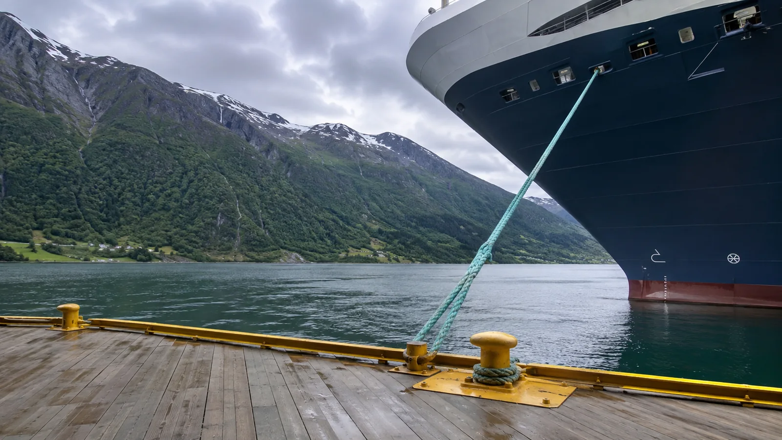 Bow of a large cruise ship docked in a mountain harbor