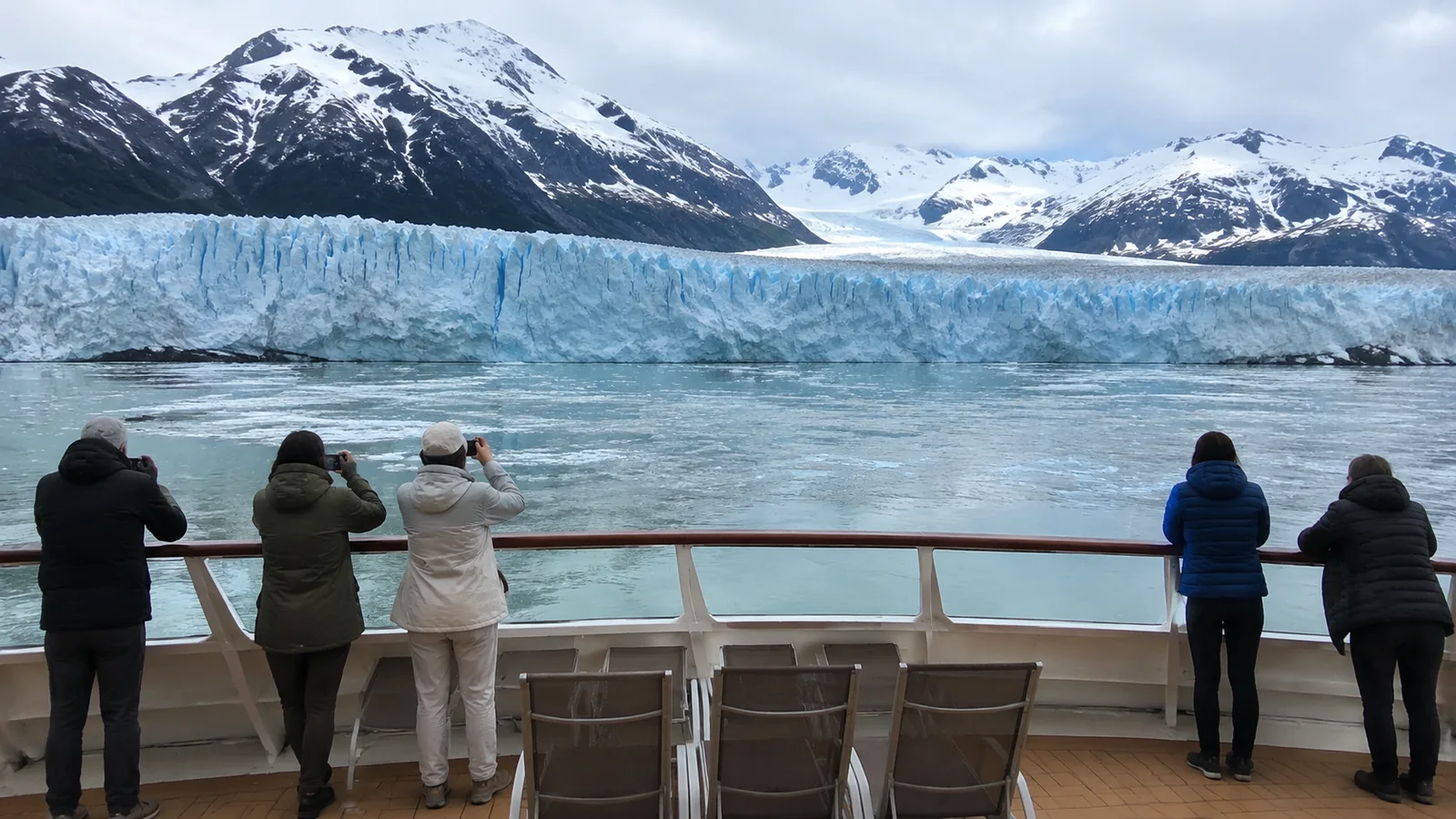 Passengers photographing a glacier from an open cruise ship deck