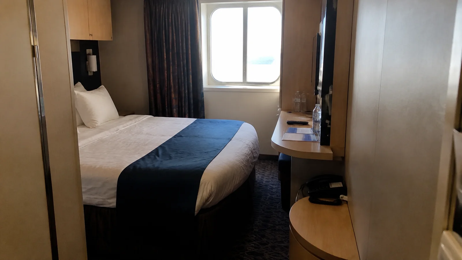 Compact cruise cabin with a double bed, desk, and window