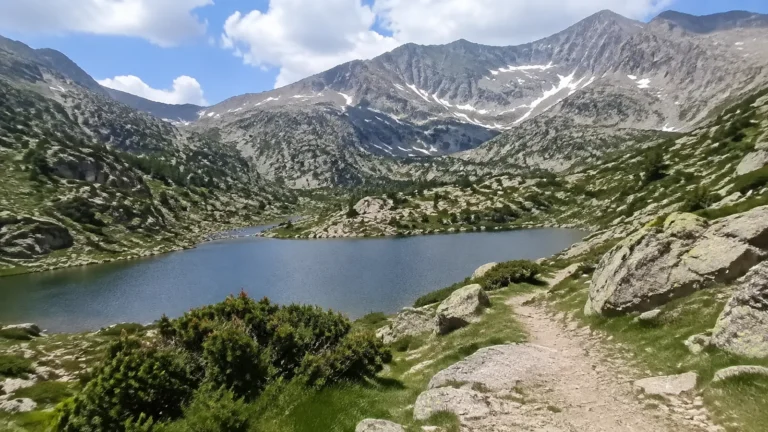 Alpine lake surrounded by rocky slopes and patches of snow.