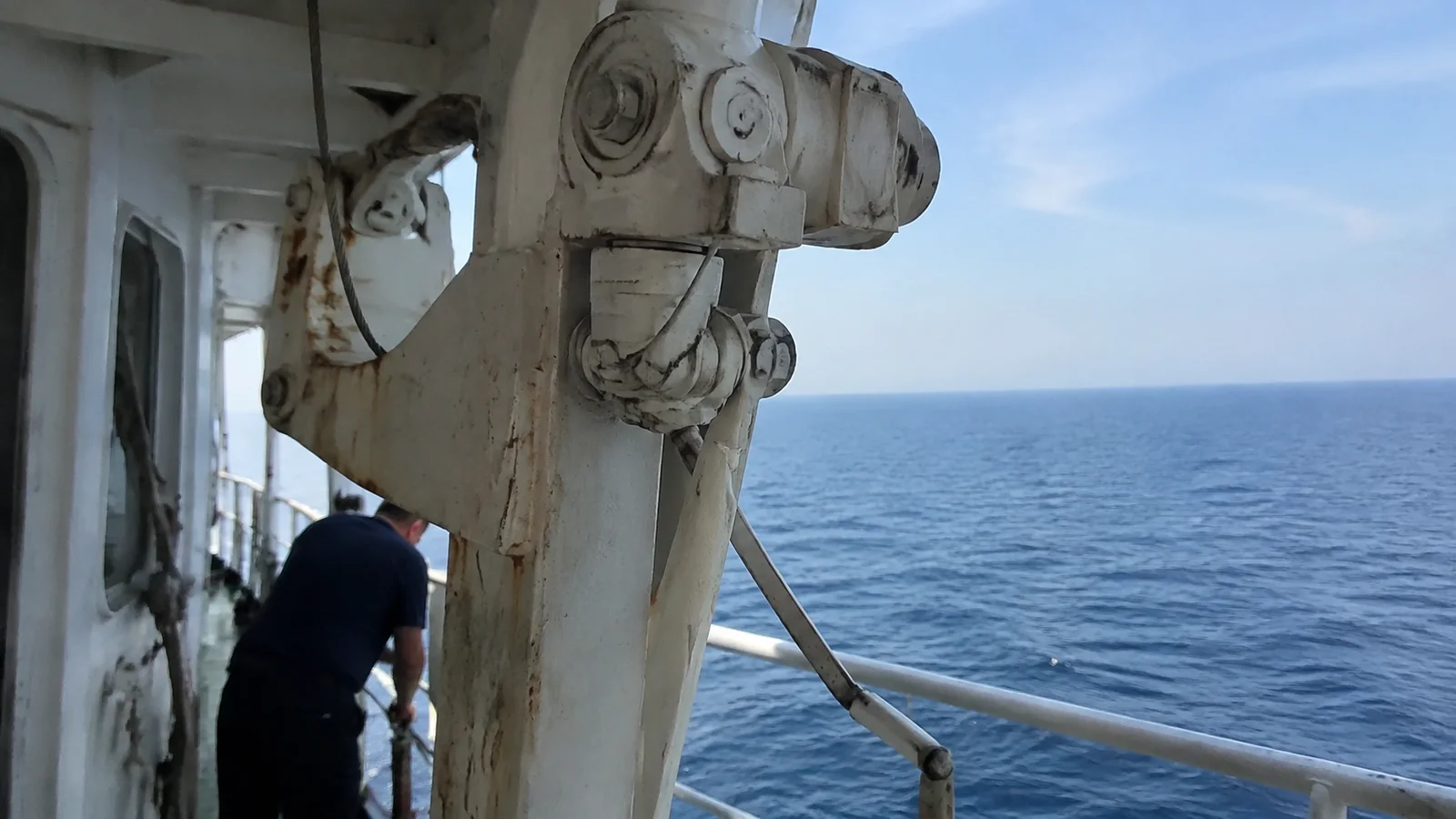 Close view of a ship's lifeboat davit and deck railing.
