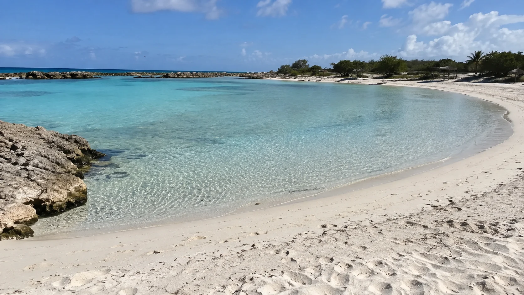 Shallow turquoise lagoon curving around the white sand of Baby Beach.