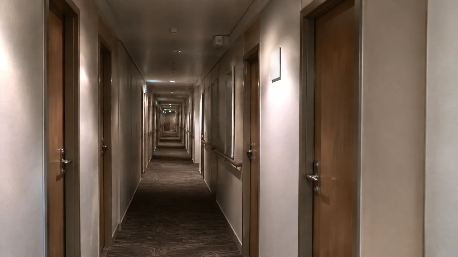 Long carpeted cruise-ship corridor lined with cabin doors.