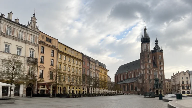 Historic town square lined with ornate buildings and a tall twin-towered church.