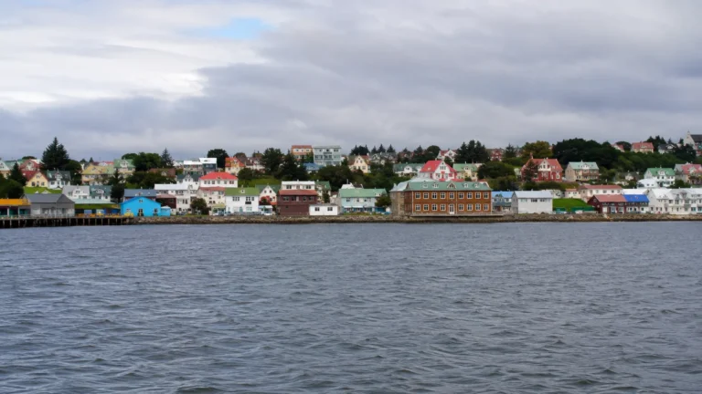 Colorful low waterfront buildings lining a harbor beneath gray clouds.