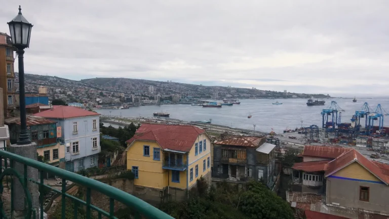 Colorful hillside houses overlooking Valparaiso's harbor and cranes.