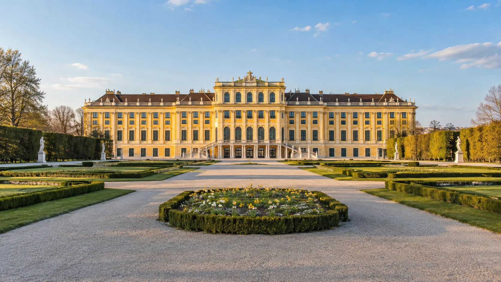 Schönbrunn Palace's yellow Baroque facade beyond formal gardens in Vienna, Austria.