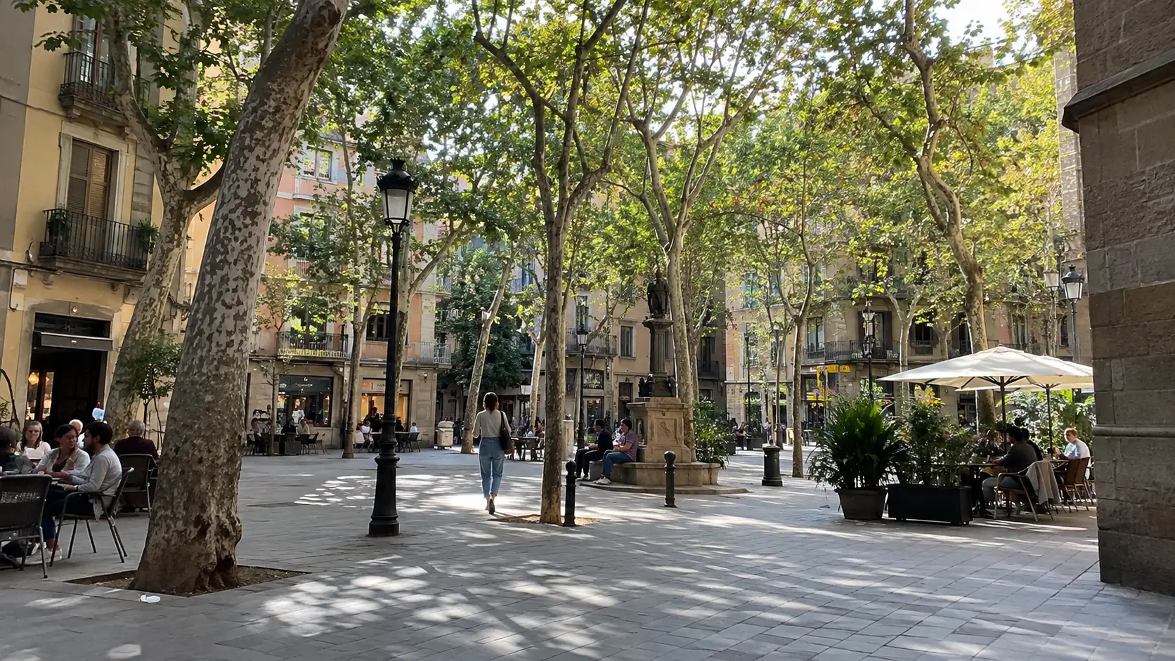 Leafy neighborhood plaza with cafe tables in Gràcia.