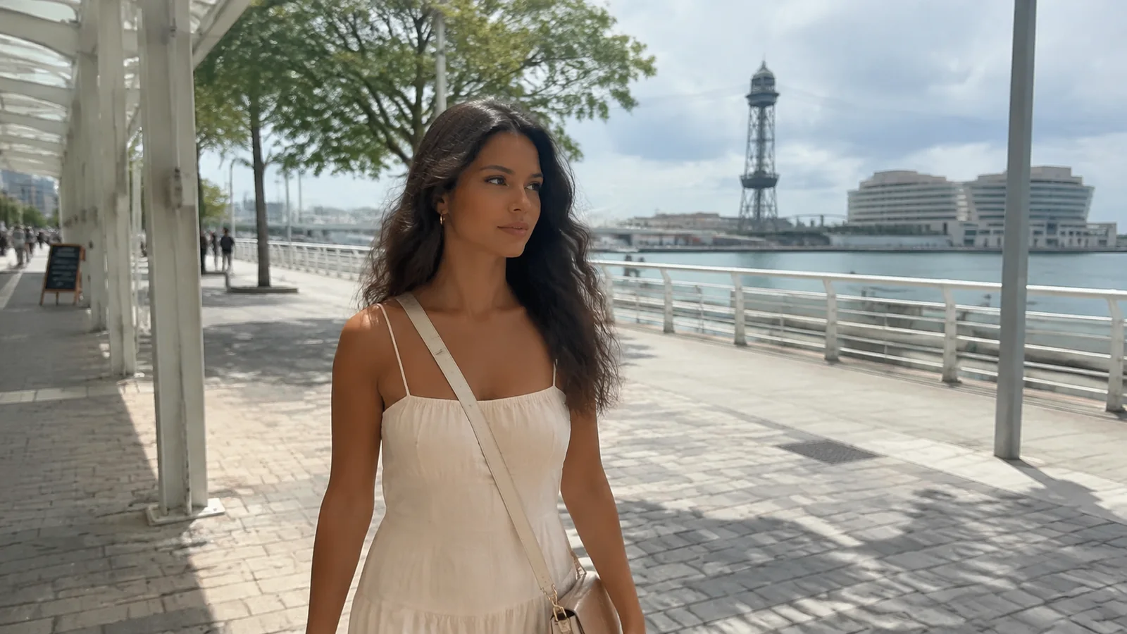 Woman walking along a shaded waterfront path beside the harbor.