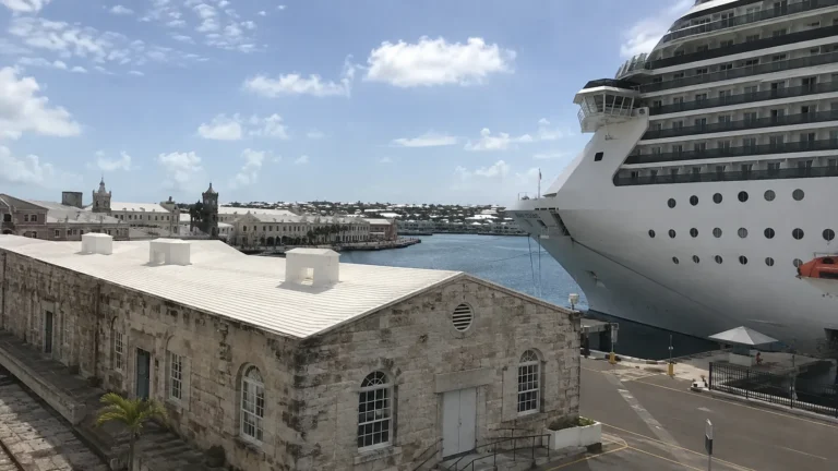 Cruise ship moored beside historic stone dockyard buildings.
