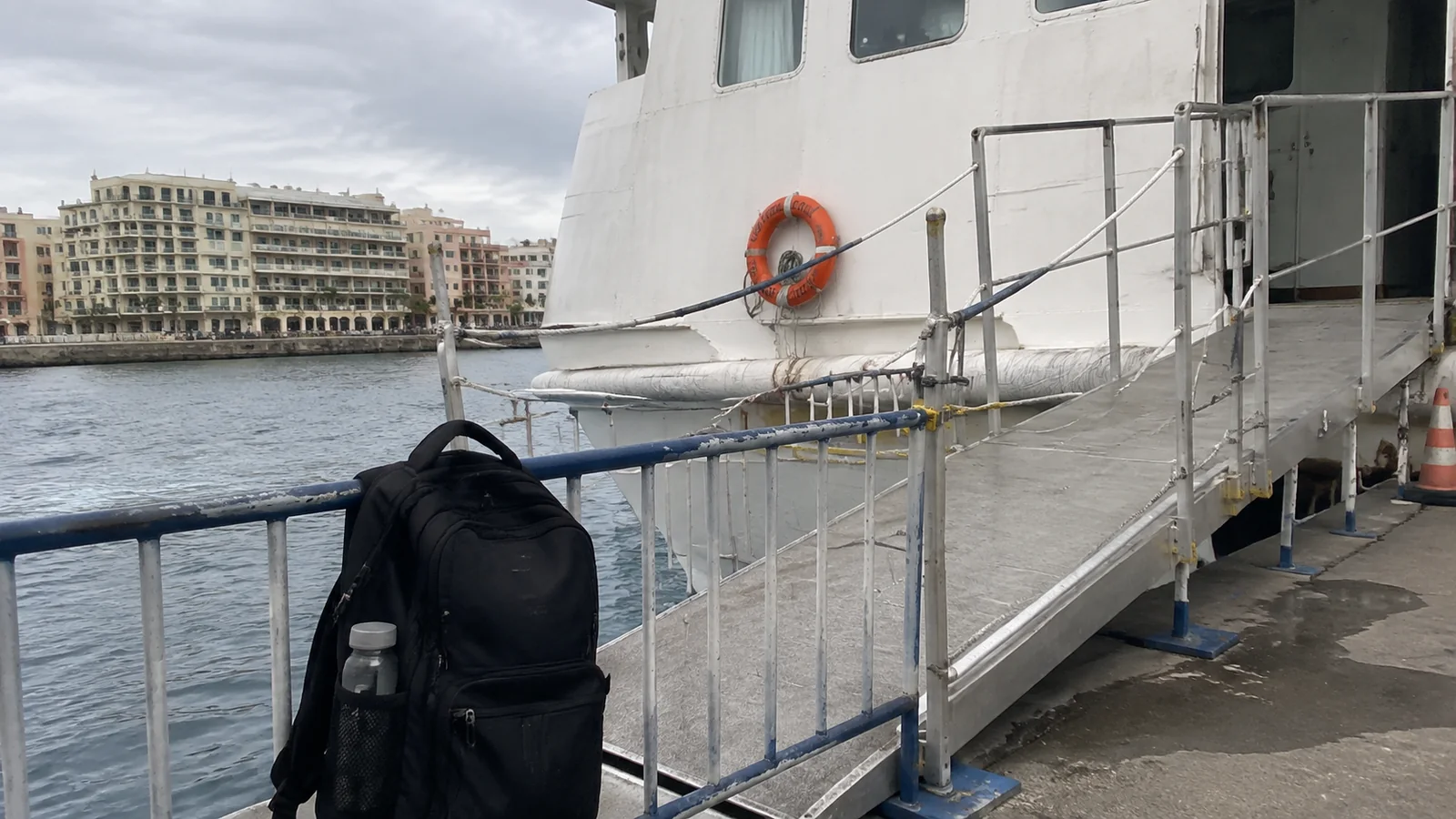 Backpack beside a ship's boarding gangway and railing.