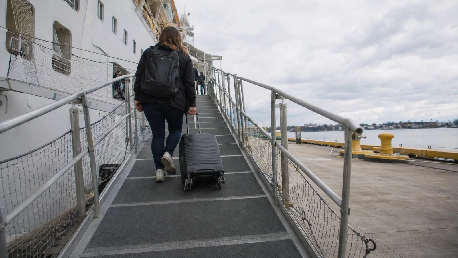 Traveler pulling a suitcase up a ship's boarding gangway.