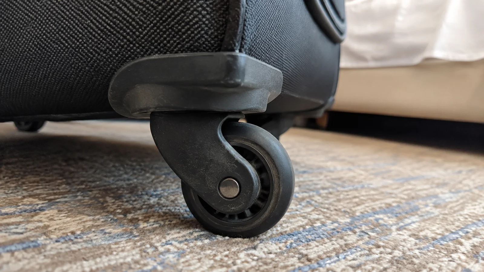 Close-up of a suitcase wheel resting on cabin carpet.