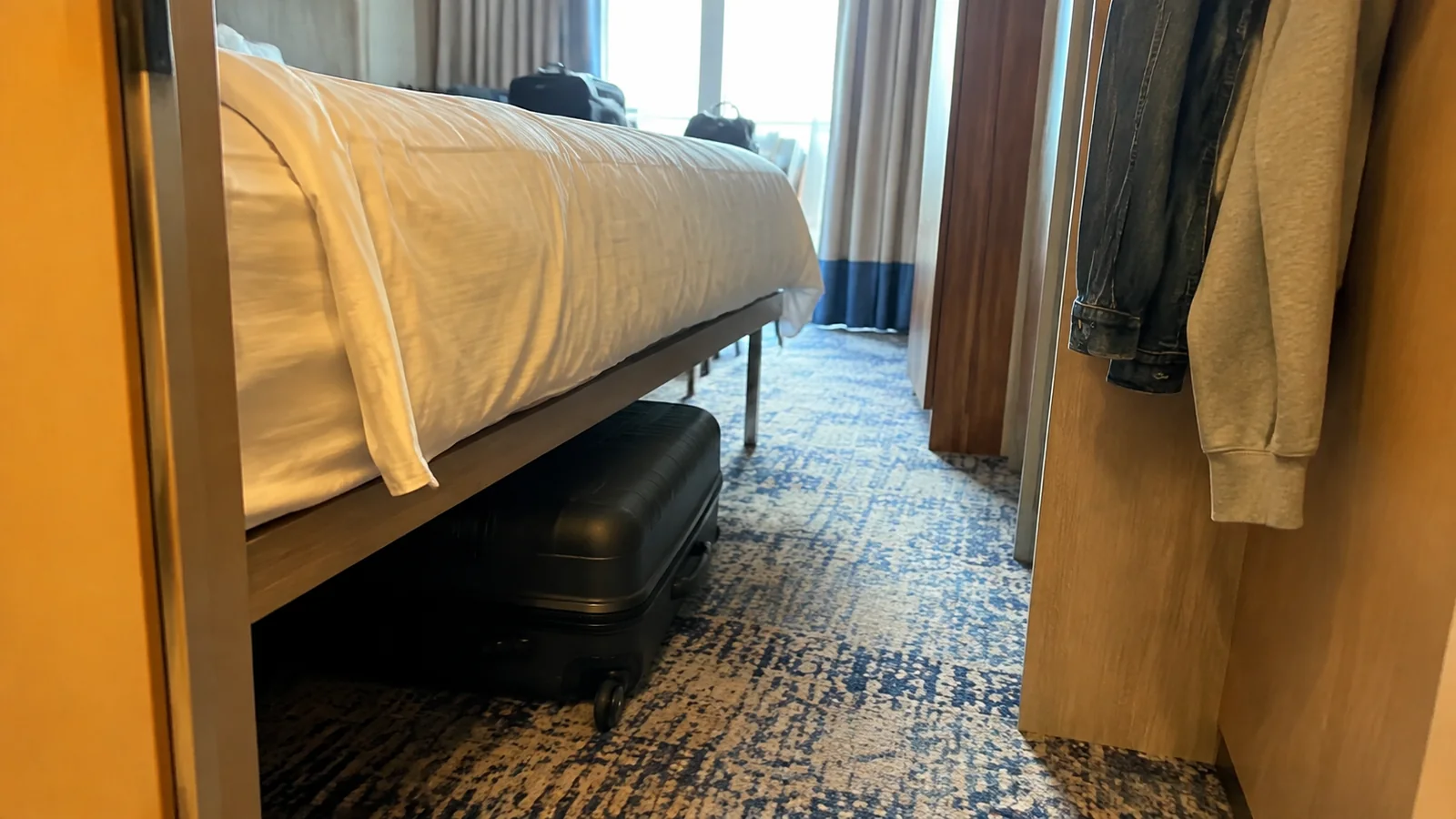 Suitcase stored underneath a cruise cabin bed.