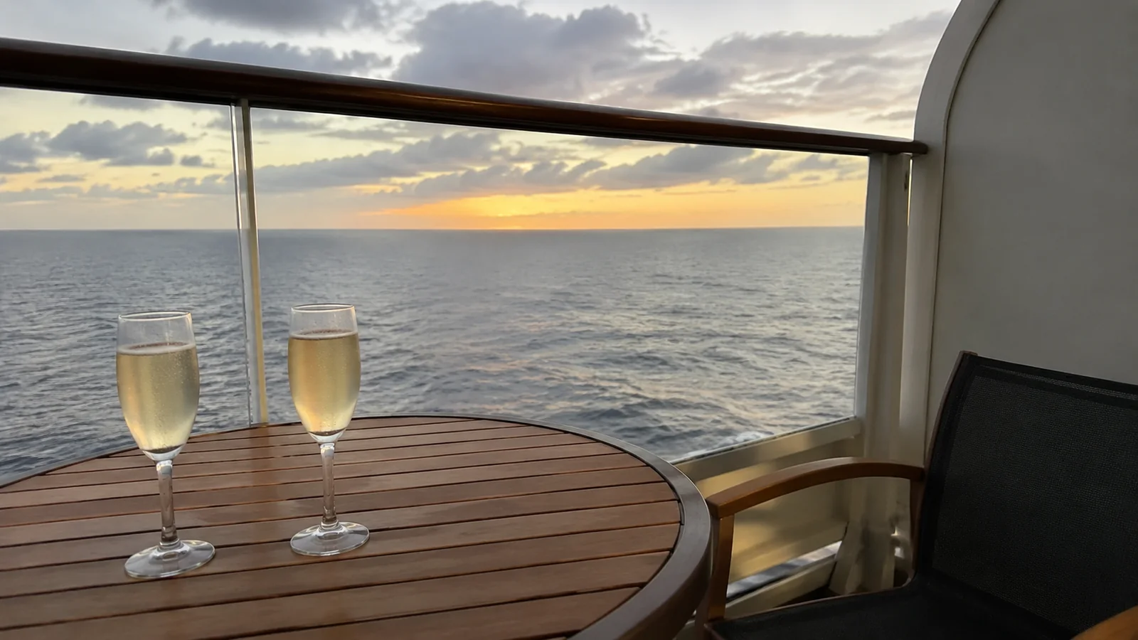 Two champagne glasses on a cruise ship balcony table at sunset