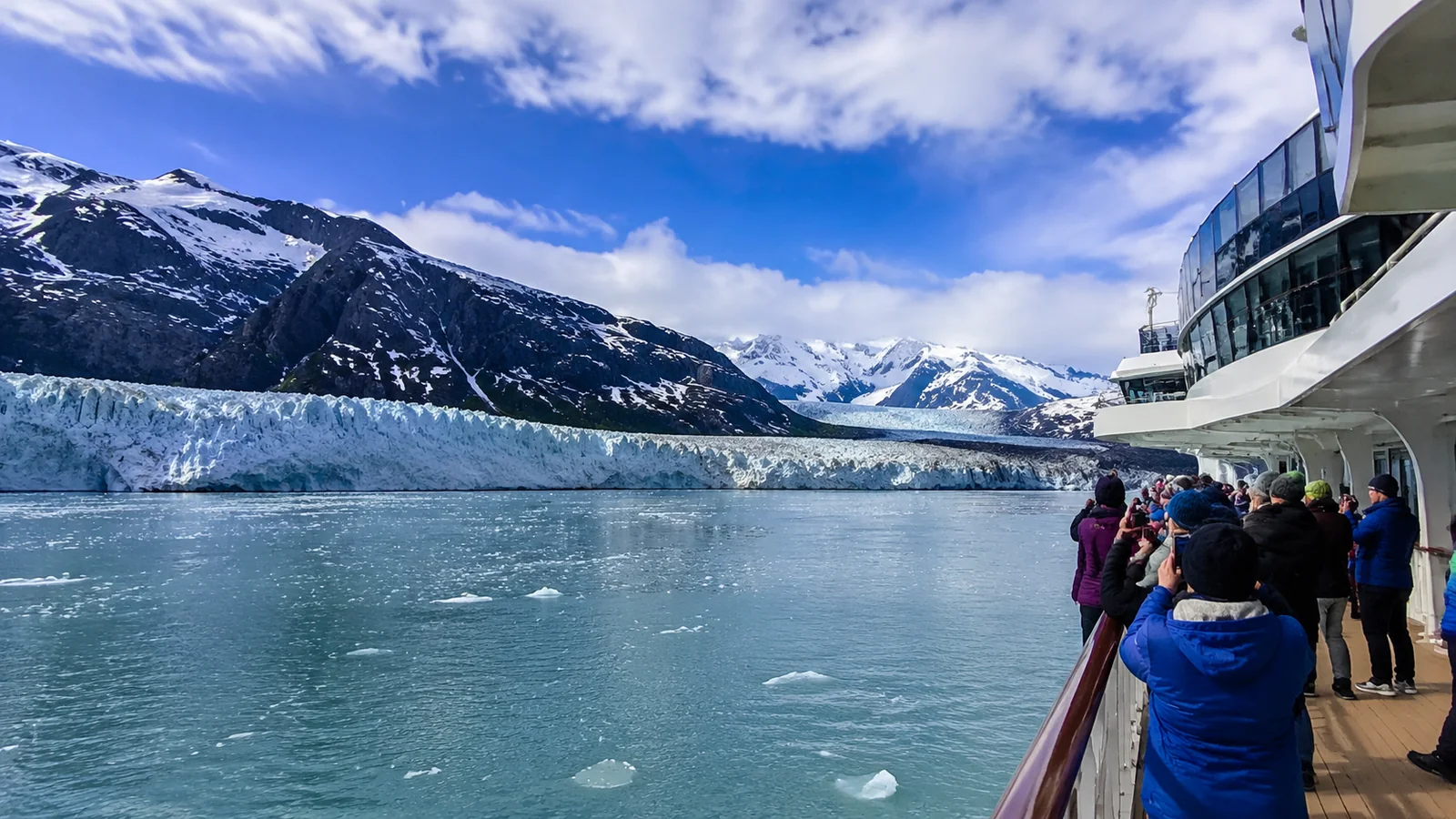 Passengers standing on a cruise ship deck viewing a glacier