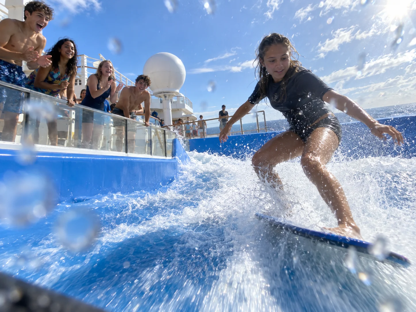 Teenagers try a surf simulator on an active cruise ship deck.