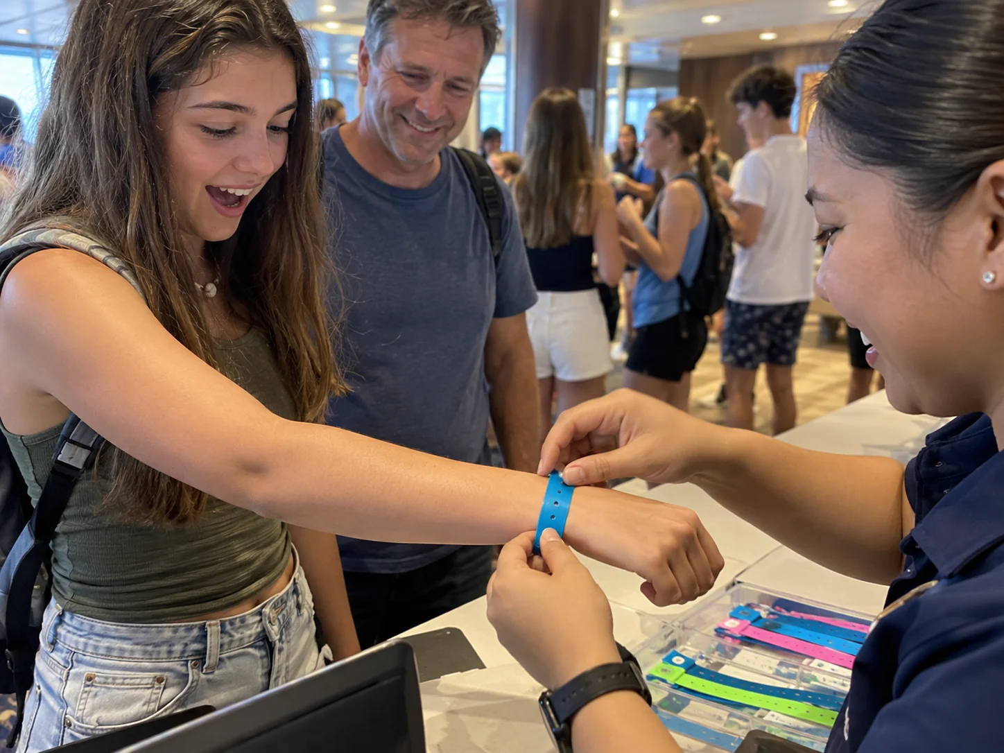 A teenager receives a youth-club wristband while a parent watches.
